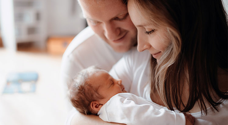 New homeowners hold a newborn baby.