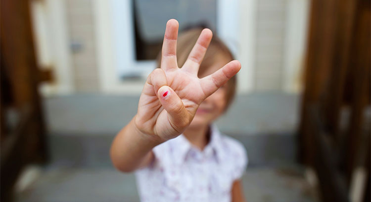 A little girl holding up three fingers.